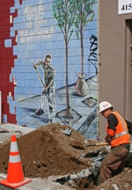 A man digging a hole in front of a mural of a man digging a hole